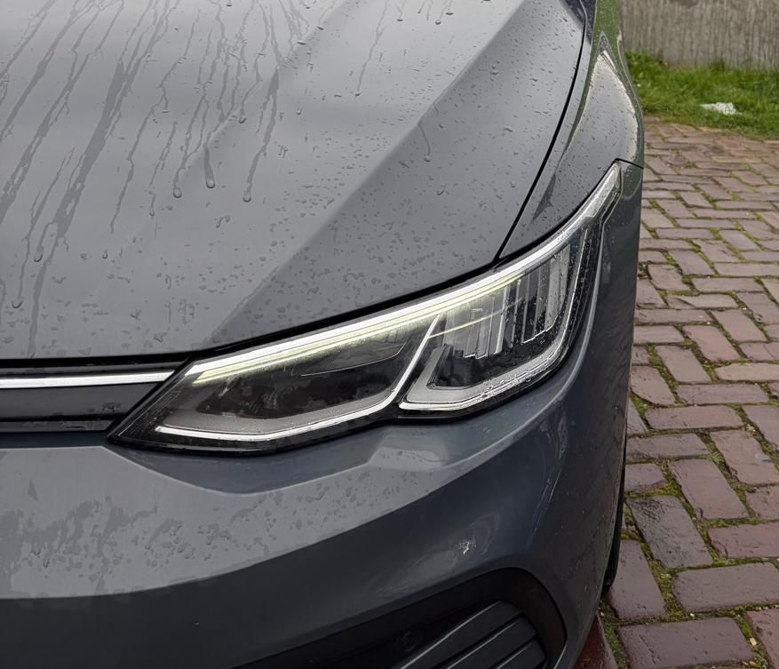 Een blauw L-bord is afgebeeld over een persoon die aantekeningen maakt in een auto; tijdens een rijexamen of rijles.
