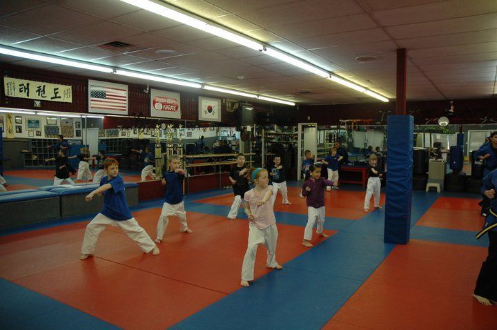 A group of children are practicing martial arts in a gym.
