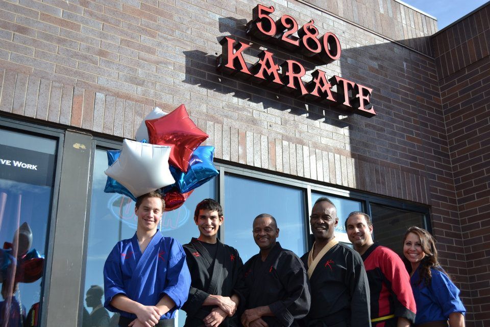 A group of people standing in front of a karate studio