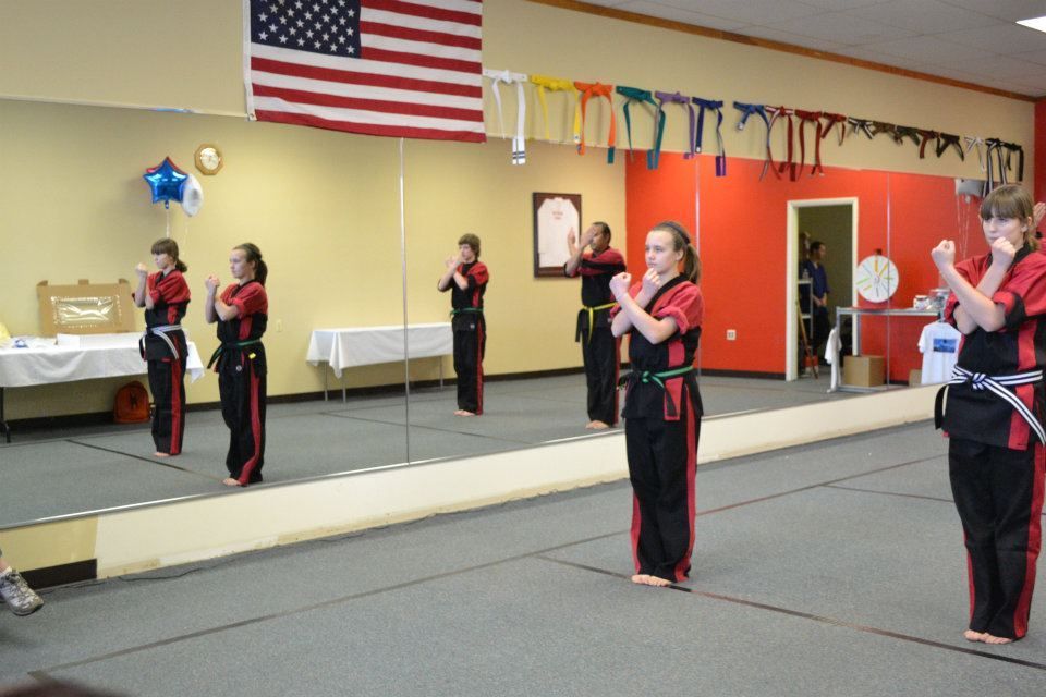 A group of girls are practicing martial arts in front of a large mirror