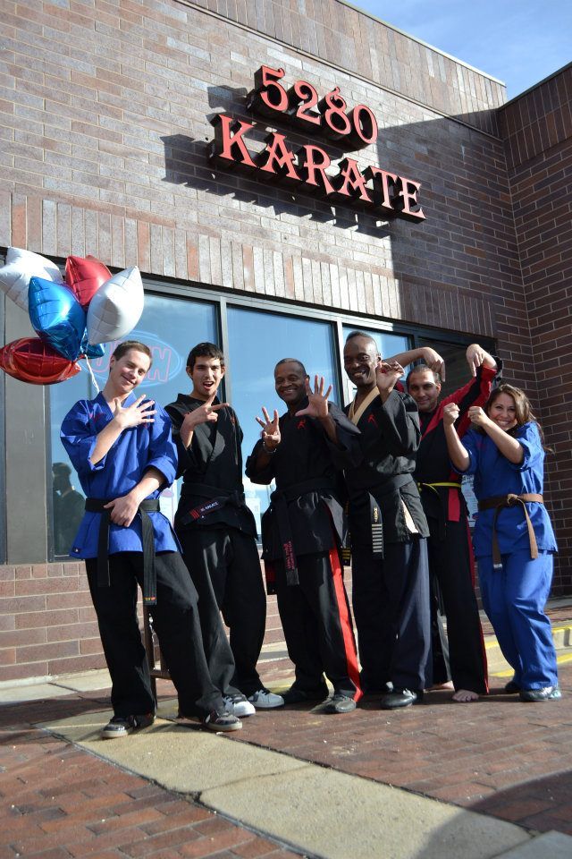 A group of people are posing for a picture in front of a karate studio.