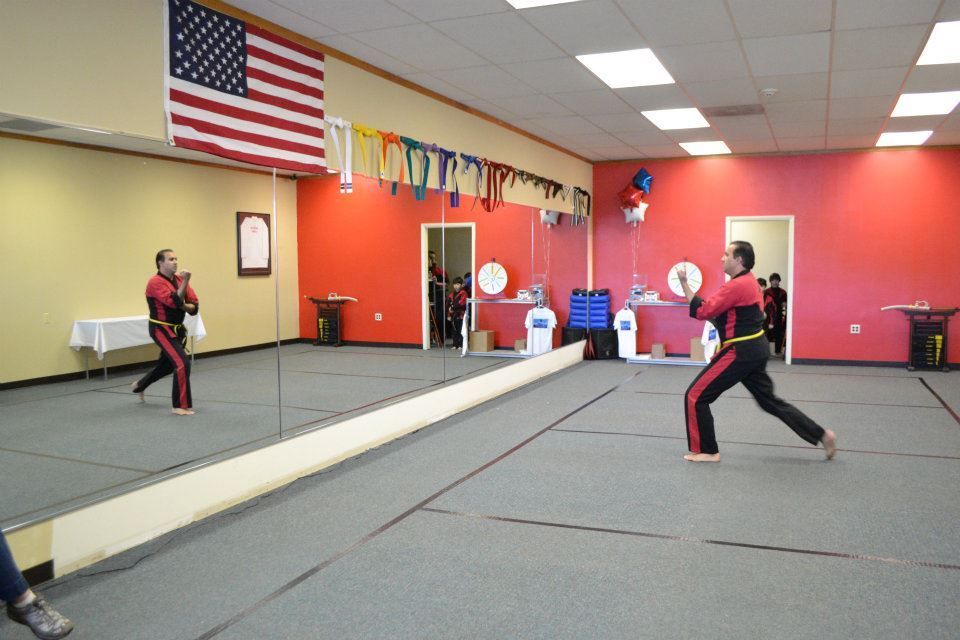 Two people are practicing martial arts in front of a large mirror.