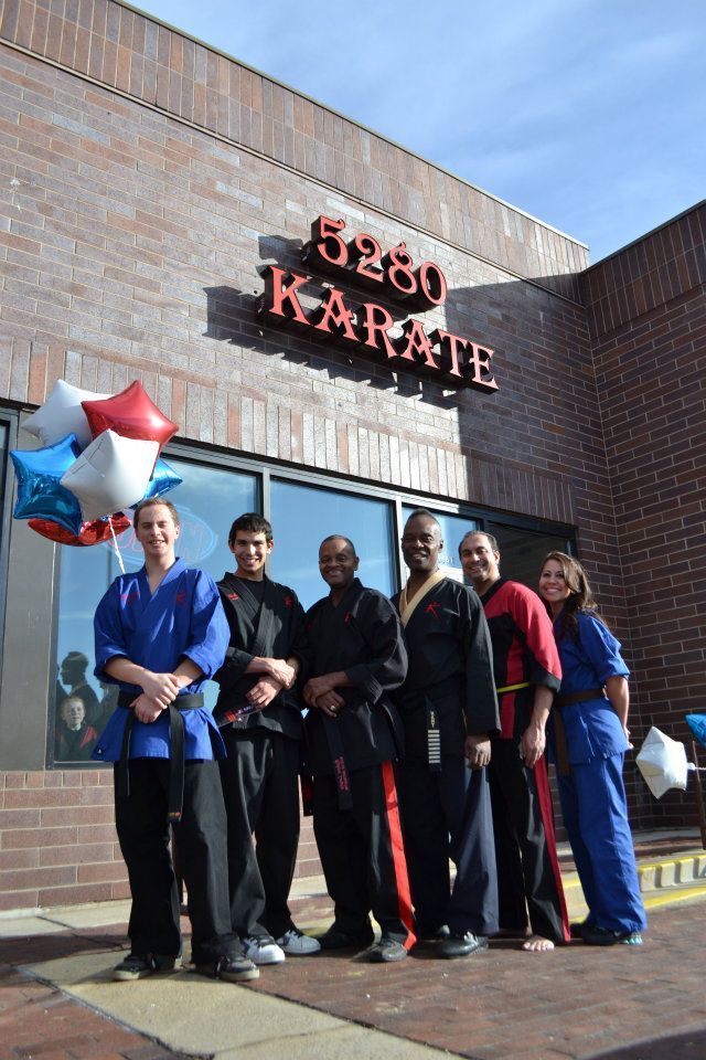 A group of people standing in front of a building that says karate