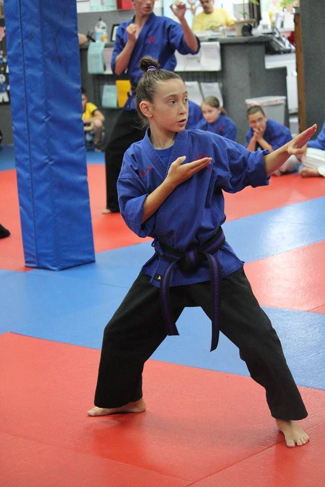 A young girl is practicing karate in a gym.