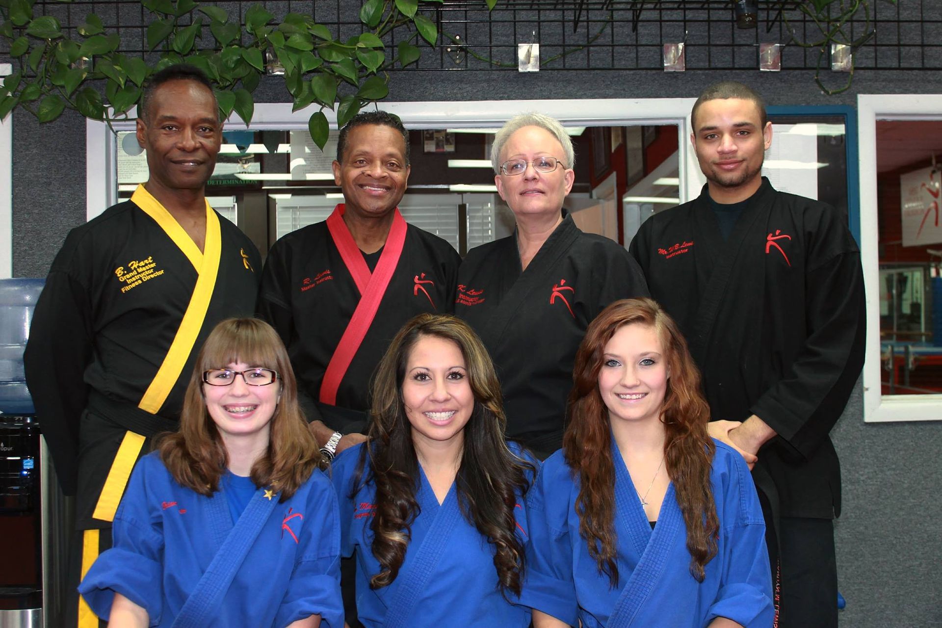A group of people posing for a picture with one of them wearing a black and yellow karate uniform