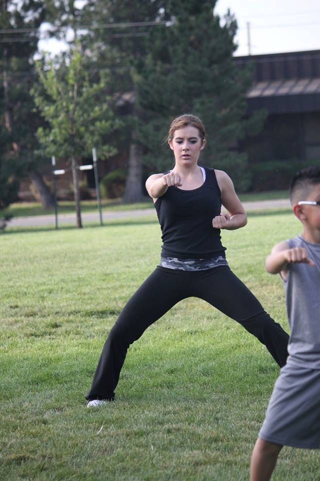 A woman and a boy are practicing martial arts in a park.