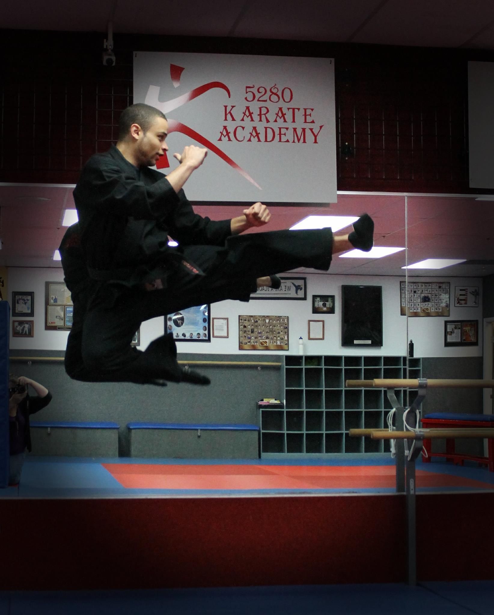 A man is jumping in the air in front of a sign that says karate academy