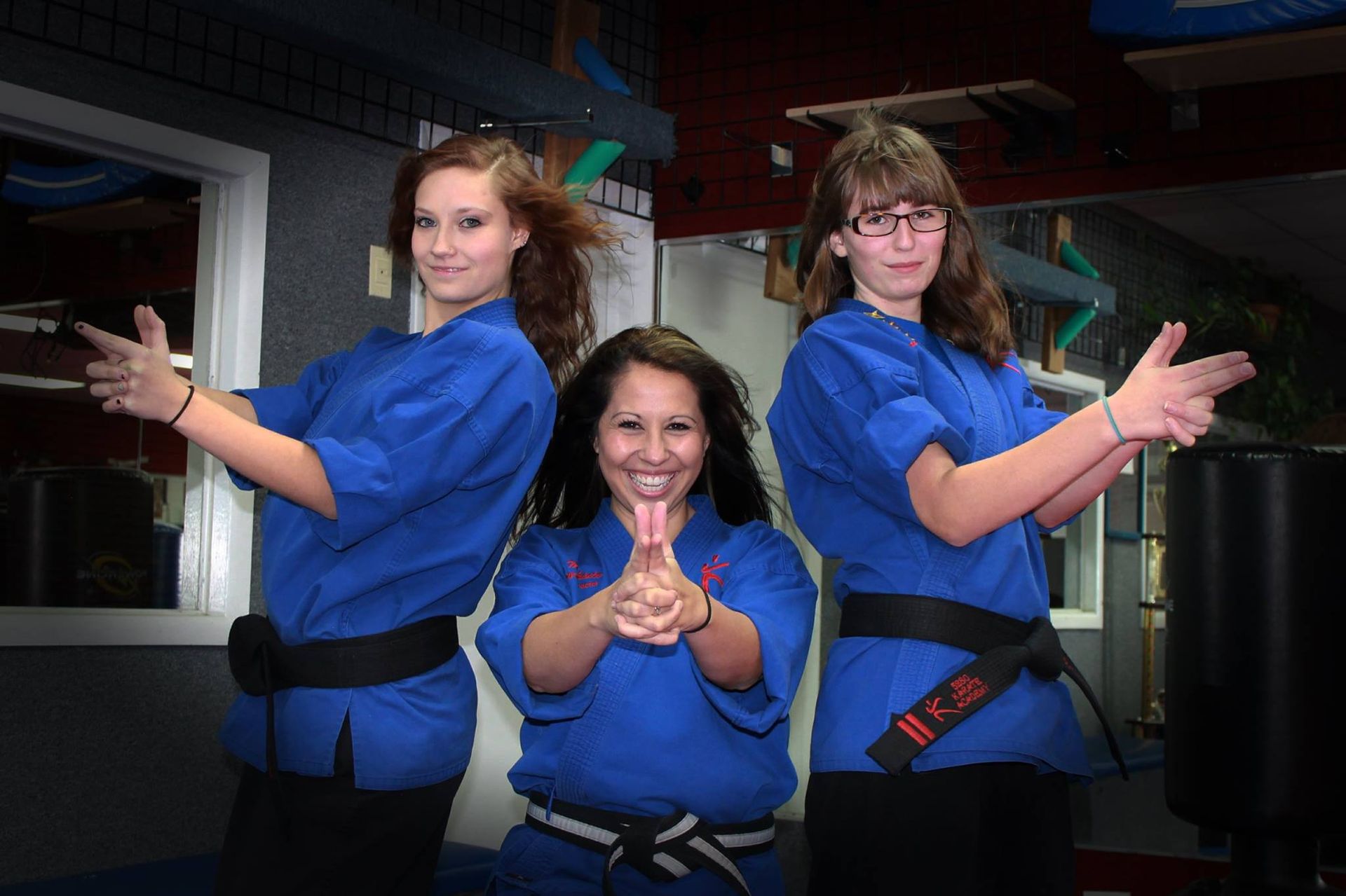 Three women in blue karate uniforms are posing for a picture