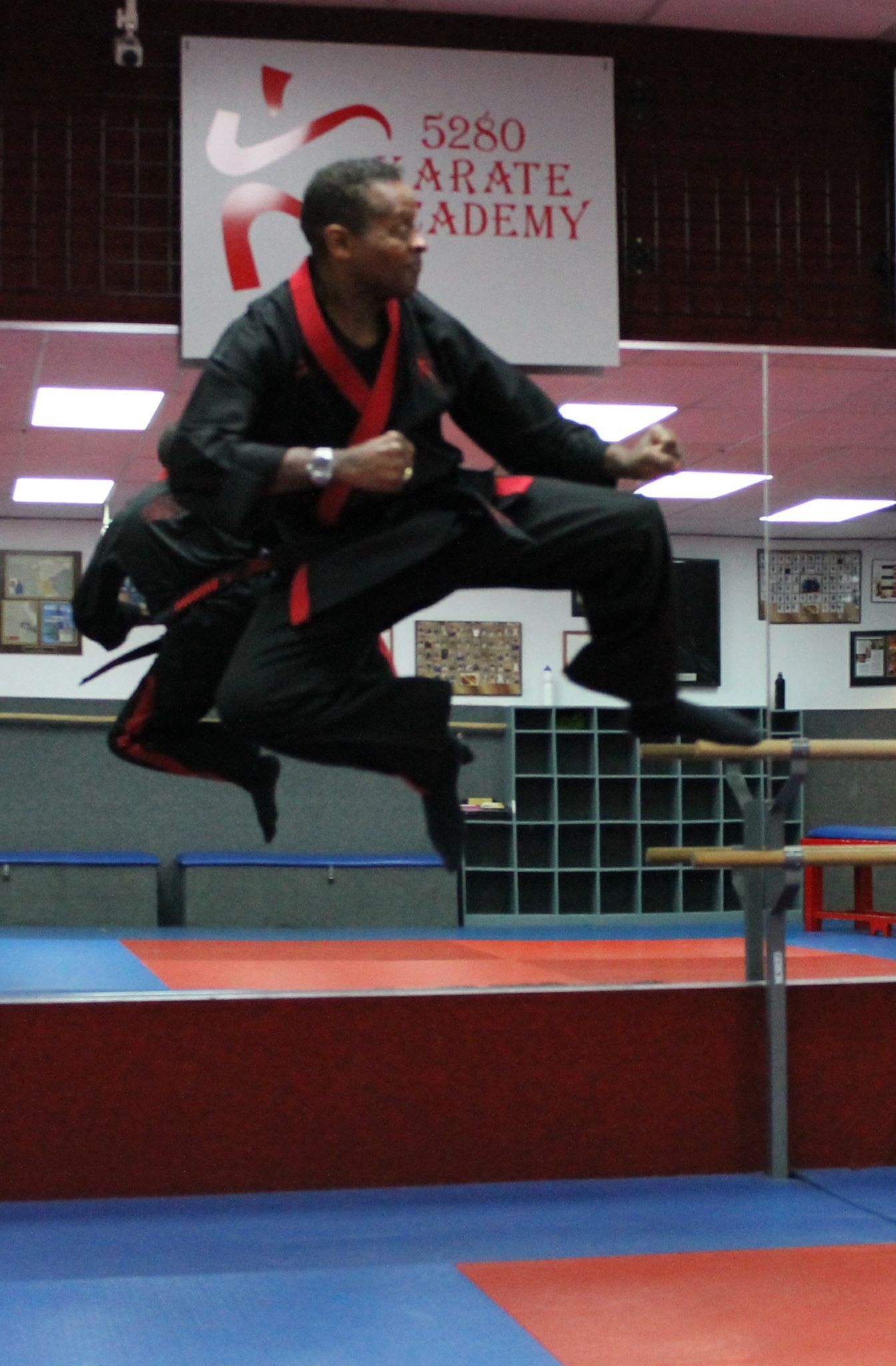 A man is jumping in the air in front of a sign that says karate academy