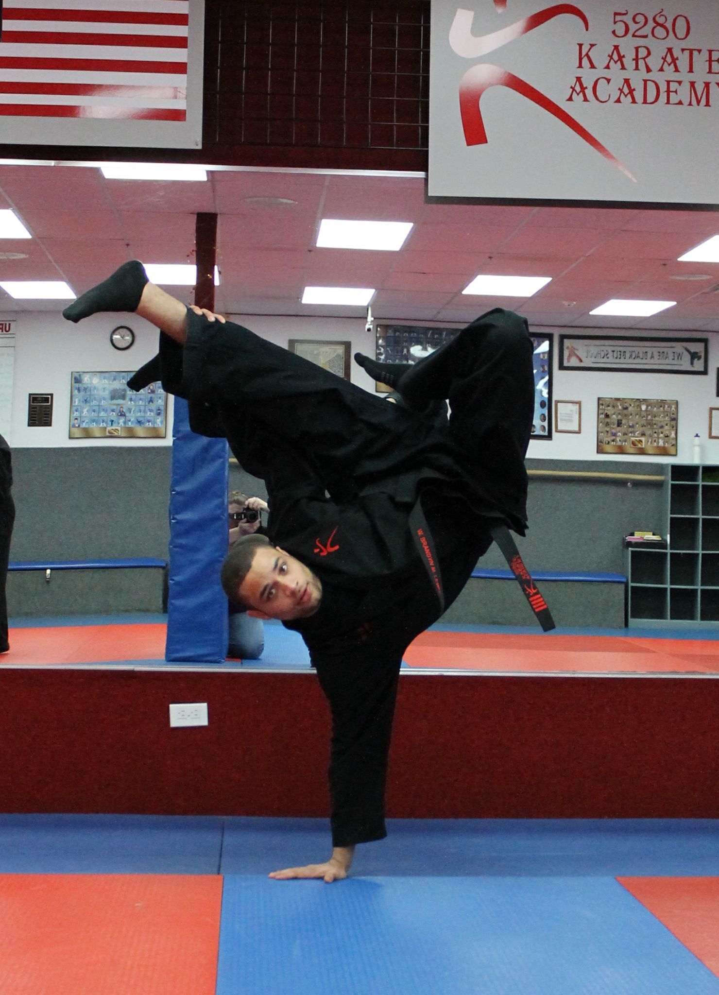 A person doing a handstand in front of a sign that says karate academy