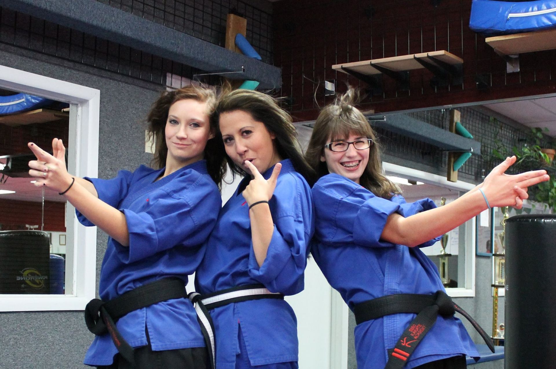 Three women in blue karate uniforms are posing for a picture