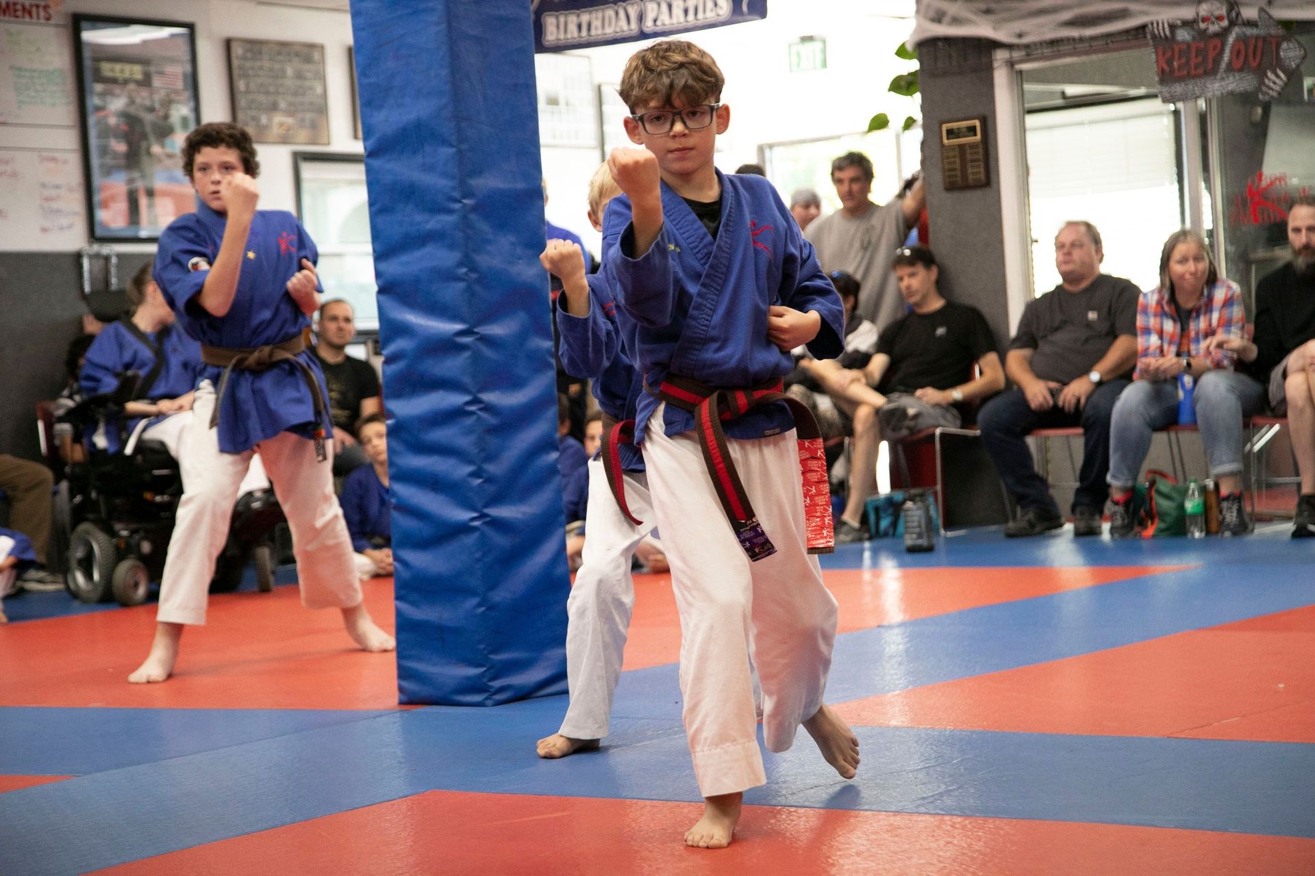 A group of young boys are practicing martial arts in a gym.