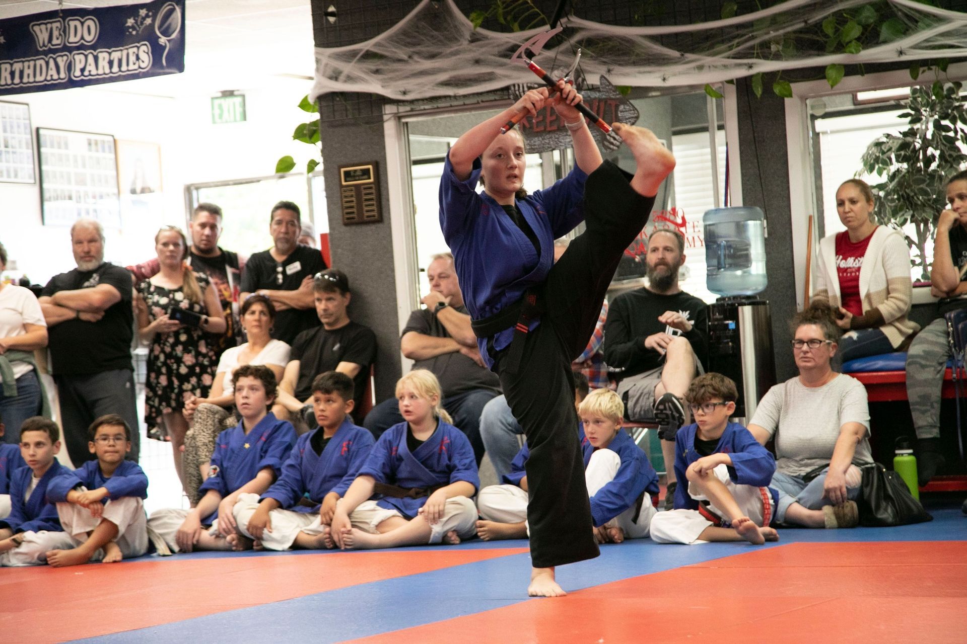 A group of people are sitting on the floor watching a person perform a karate move.