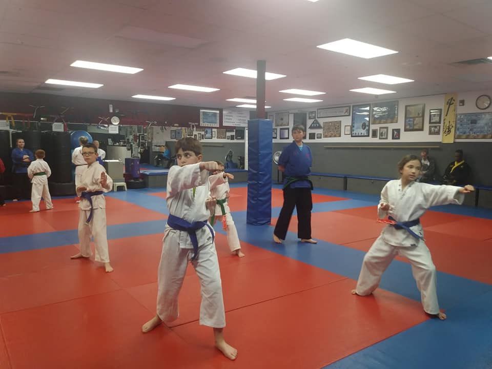 A group of young boys are practicing karate in a gym.