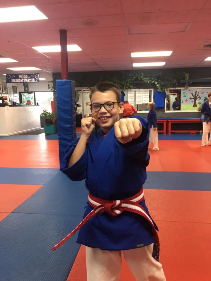 A young boy wearing a blue karate uniform and a red belt