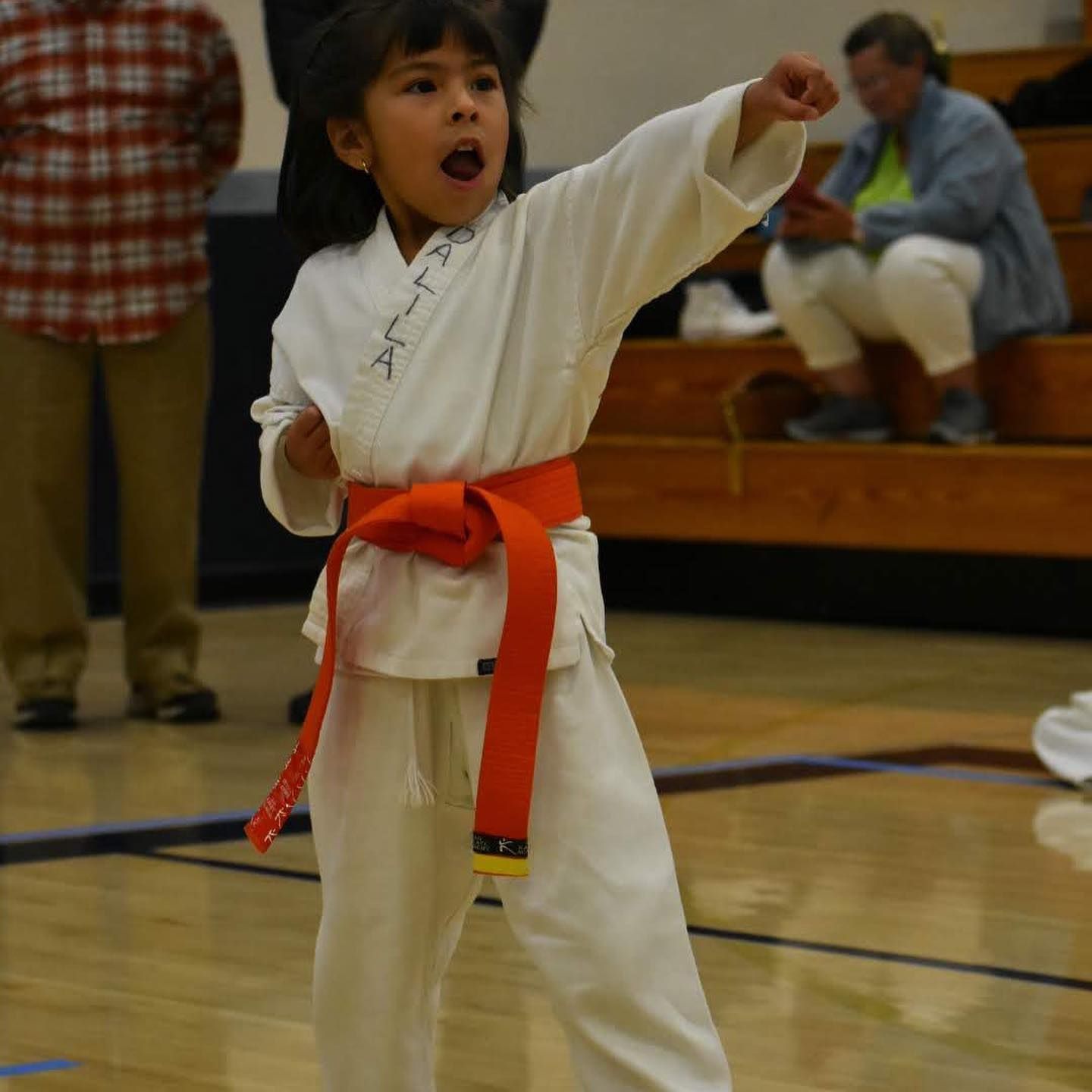 A young boy in a white karate uniform with an orange belt