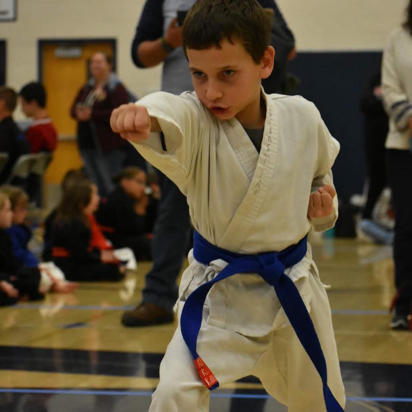 A young boy in a white karate uniform with a blue belt