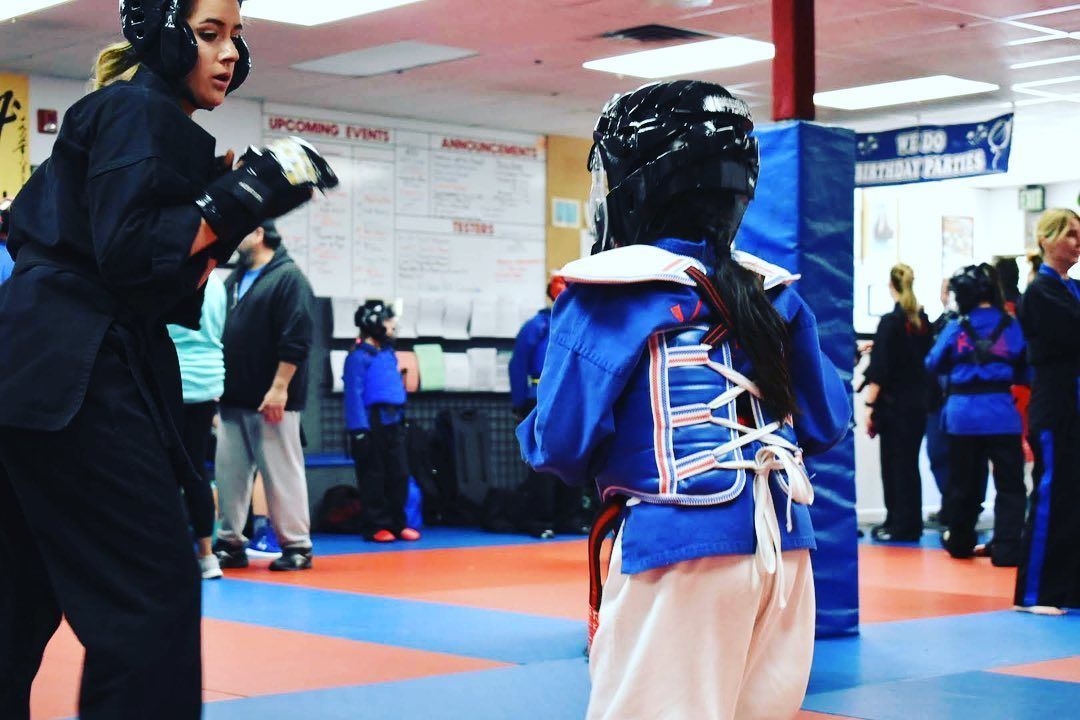 A group of young girls are practicing martial arts in a gym.