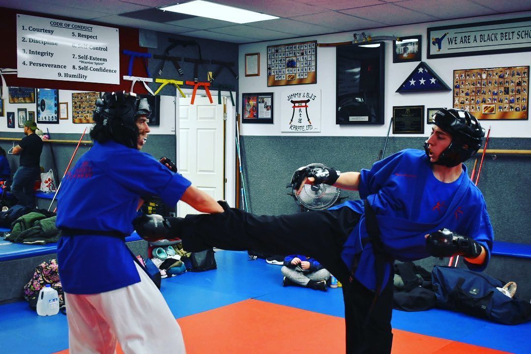 Two people are practicing martial arts in a gym