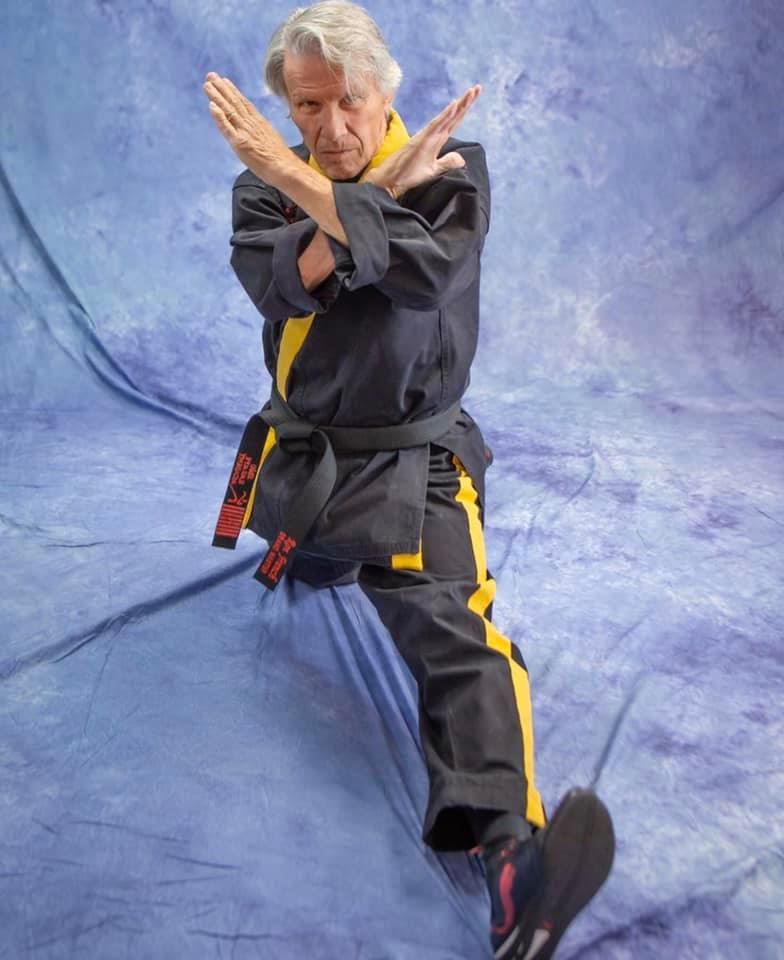 A man is wearing a black and yellow karate uniform