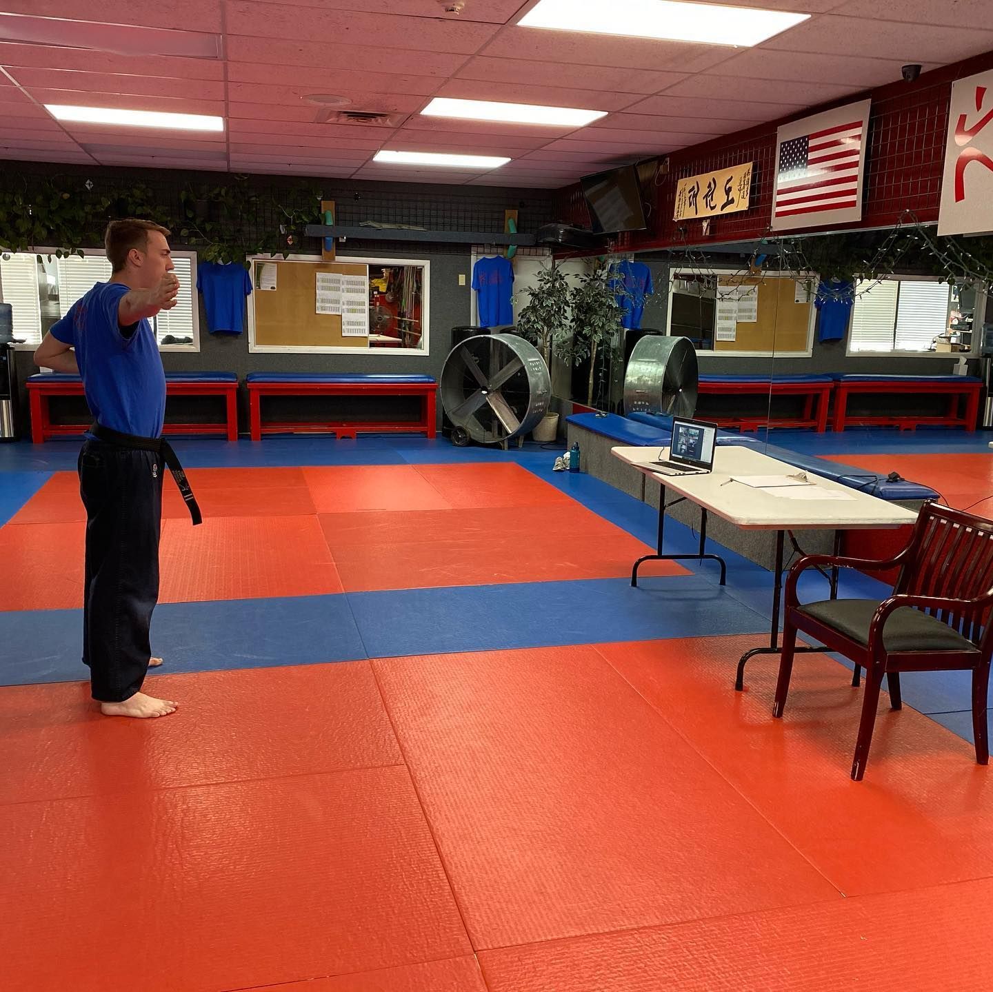 A man in a blue shirt is standing in a karate dojo