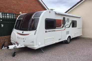 A white caravan is parked in front of a house.