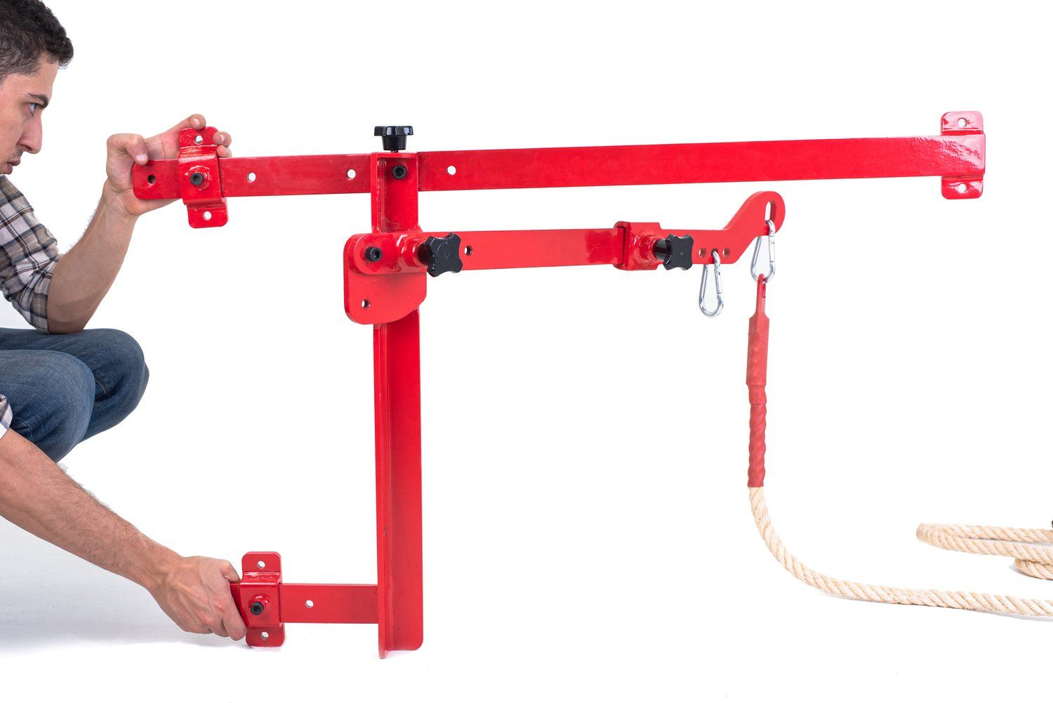 A man is kneeling down next to a red object with a rope attached to it.