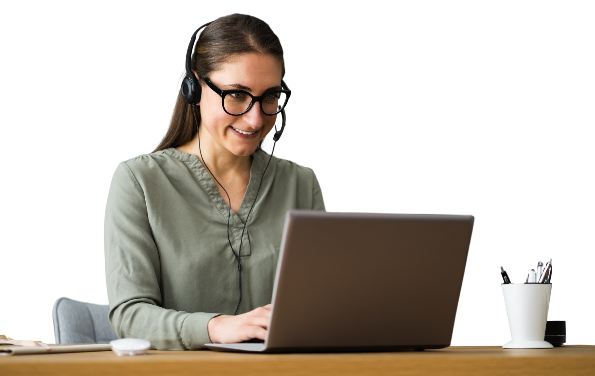 A woman wearing a headset is sitting at a desk using a laptop computer.