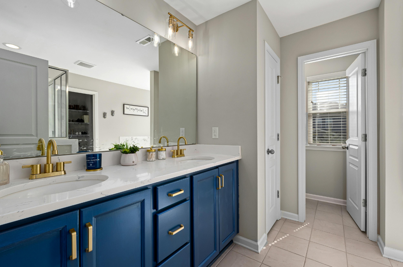 A bathroom with blue cabinets and a large mirror.