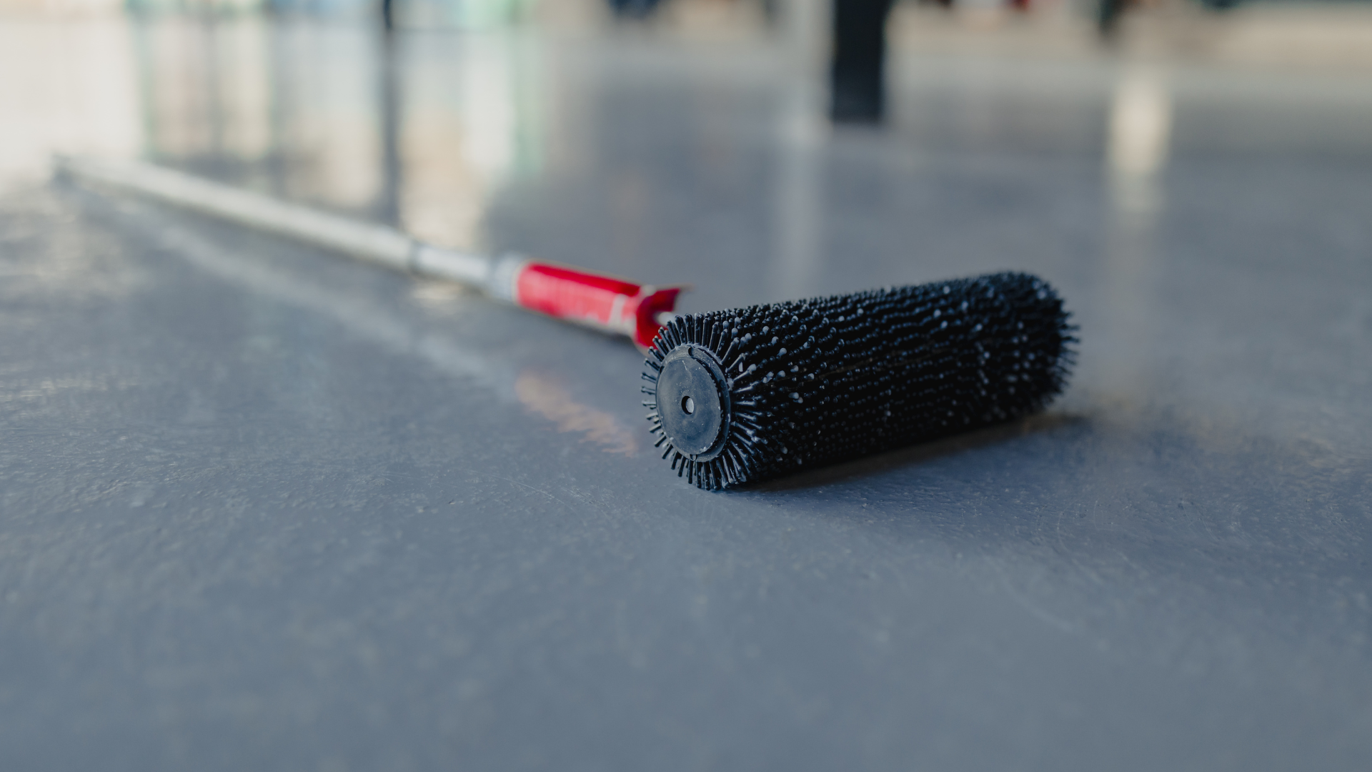 A paint roller is sitting on a concrete floor.