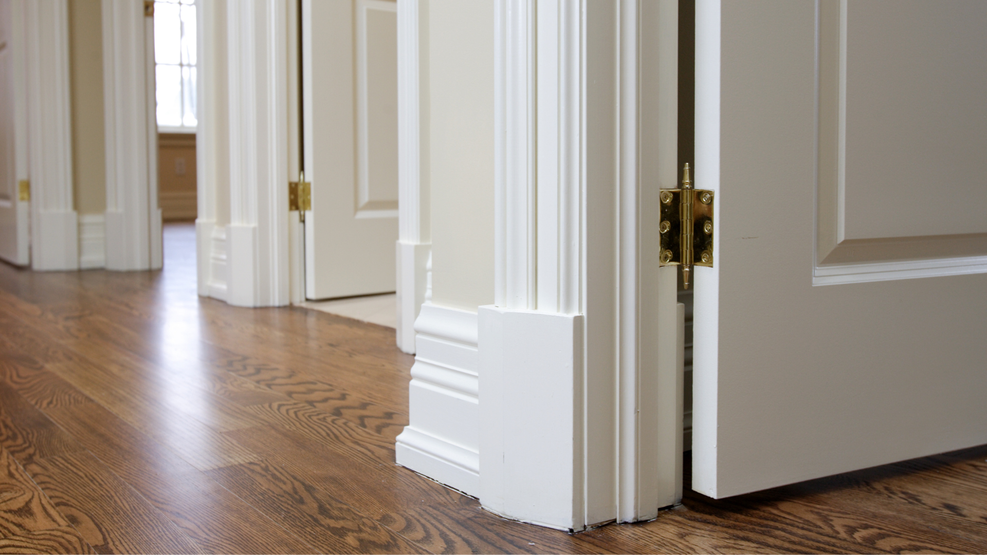 A hallway with hardwood floors and white trim and doors.