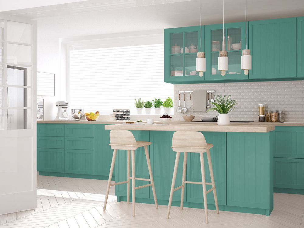 A modern kitchen with turquoise cabinets and stools.