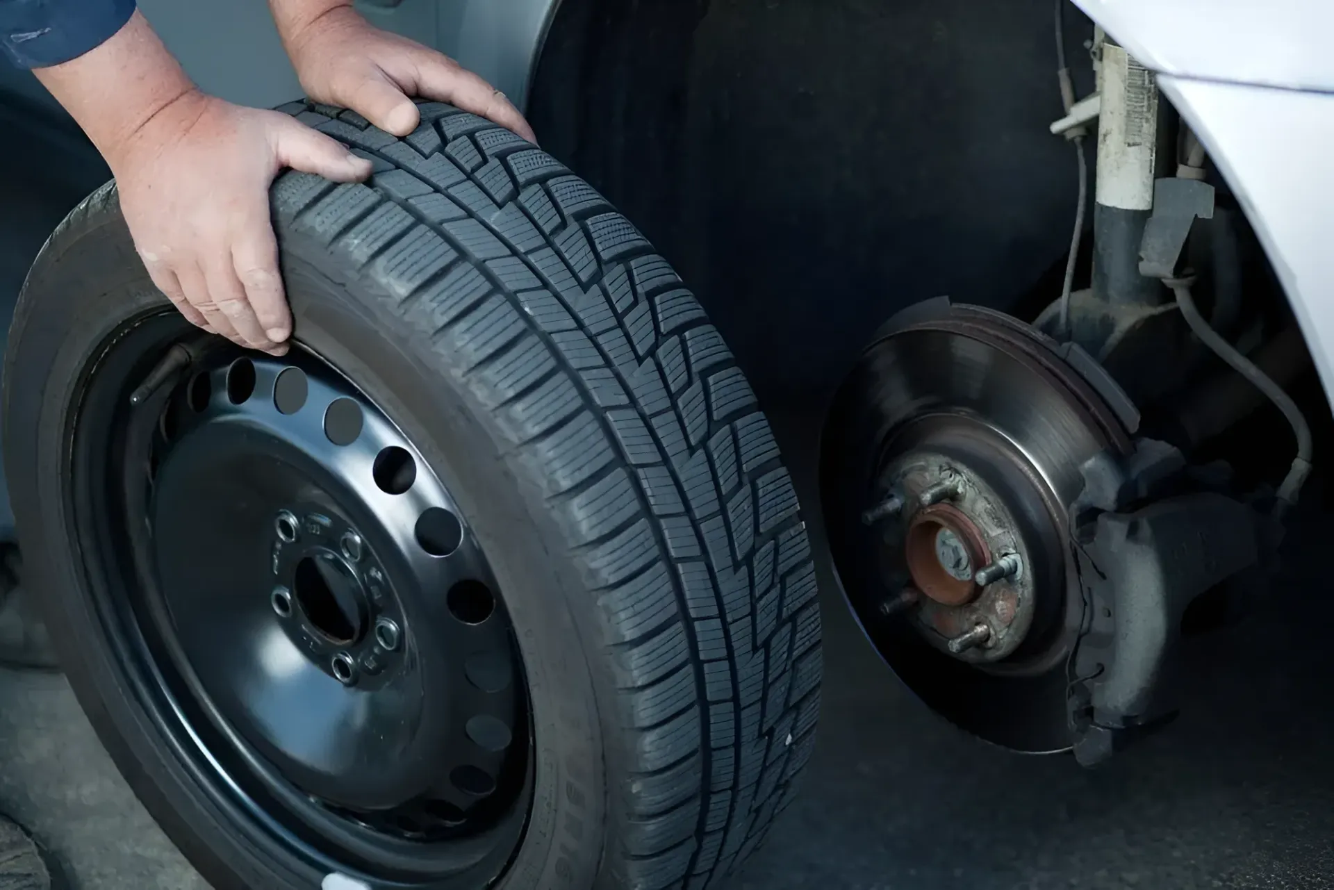 Person Changing a Car Tire; Tire in Hand, Car Wheel Removed — Innisfail Pro Motors in Mission Beach, QLD
