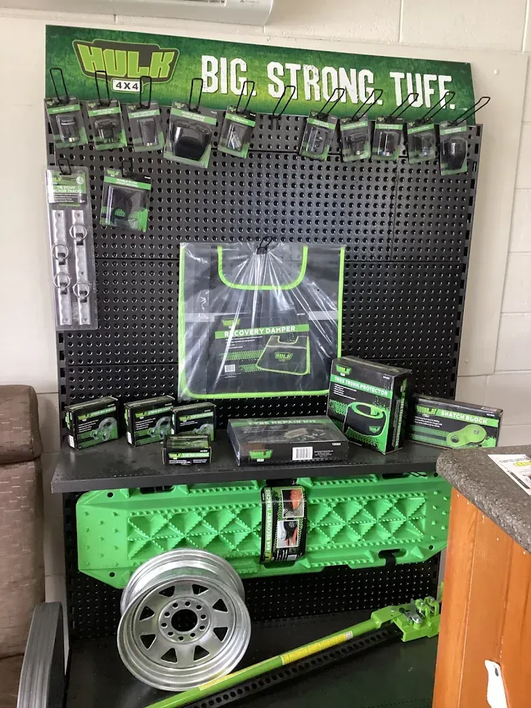 Display of HULK brand off-road accessories: green and black pegboard with tools and recovery gear, plus a wheel — Innisfail Pro Motors in Innisfail, QLD