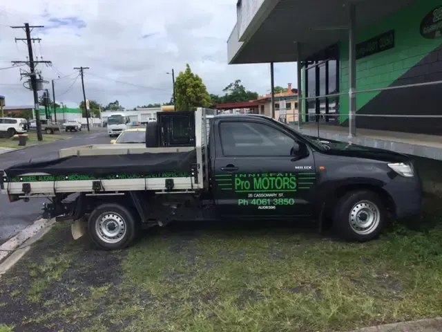 Black pickup truck parked on grass in front of building with 