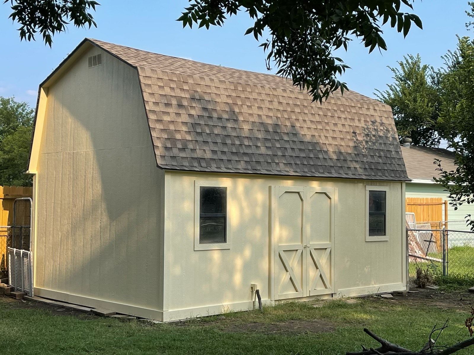 A white barn with a brown shingle roof