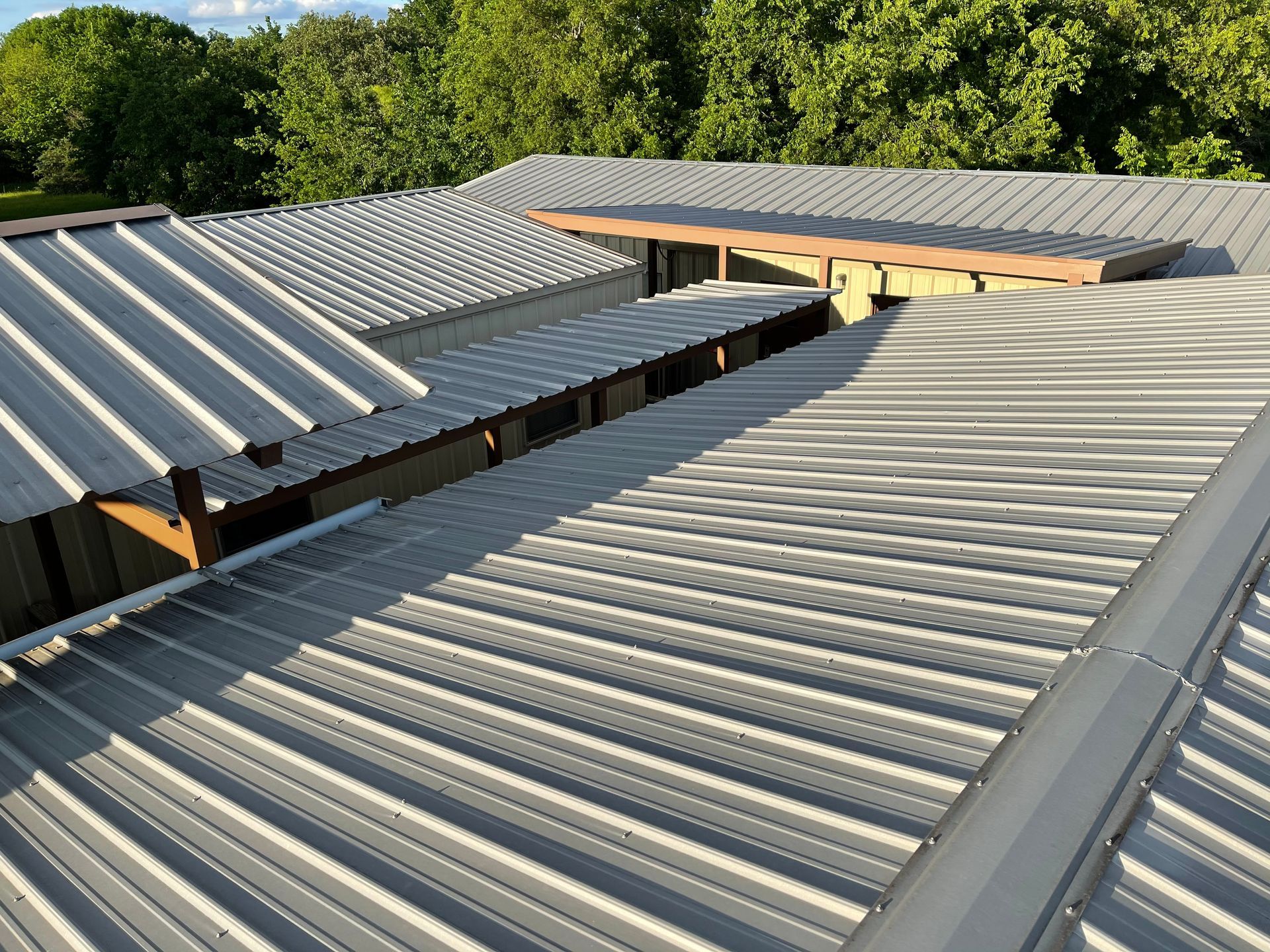 A close up of a metal roof with trees in the background.