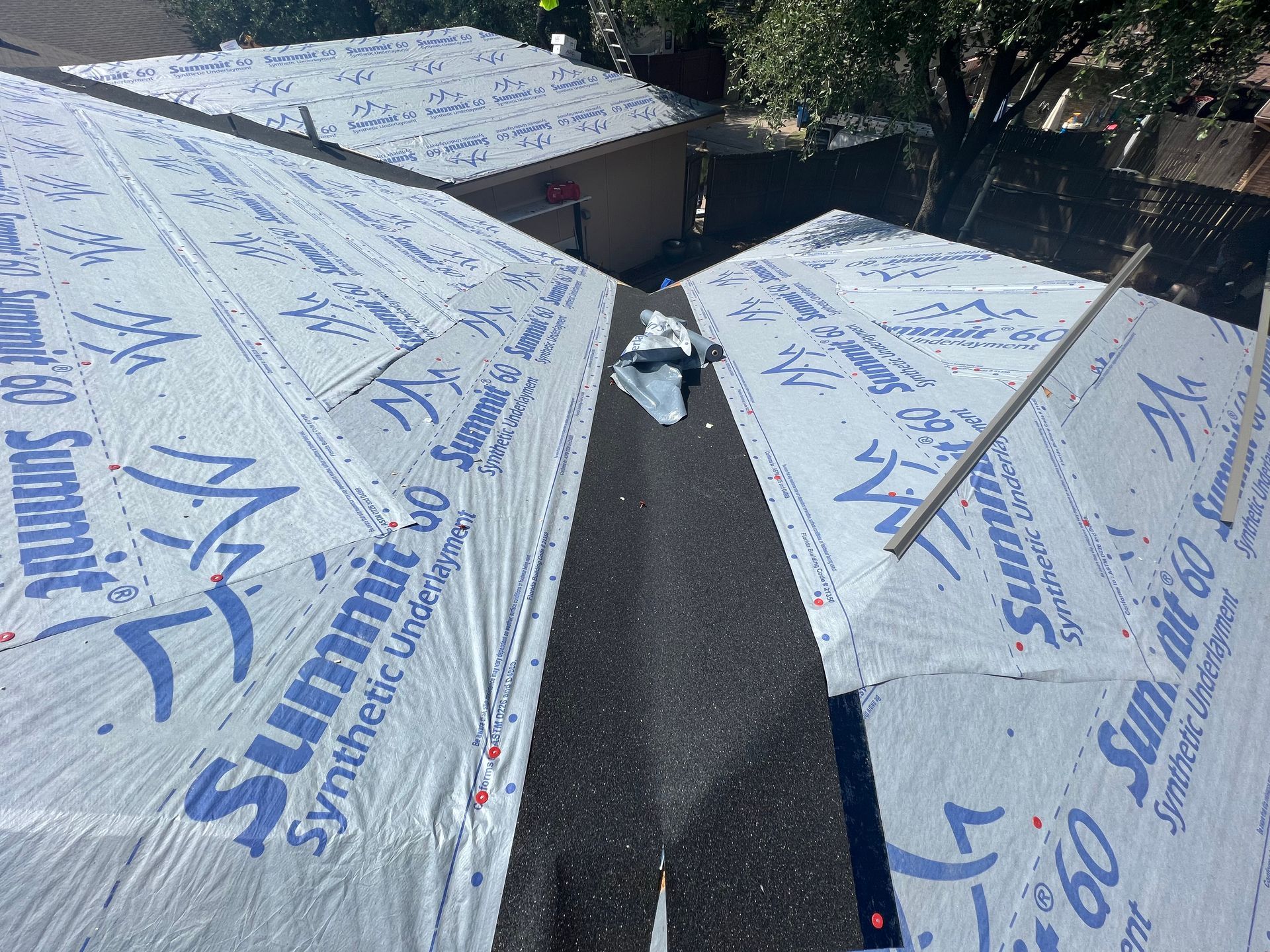 A roof is being covered with a sheet of summit synthetic insulation.