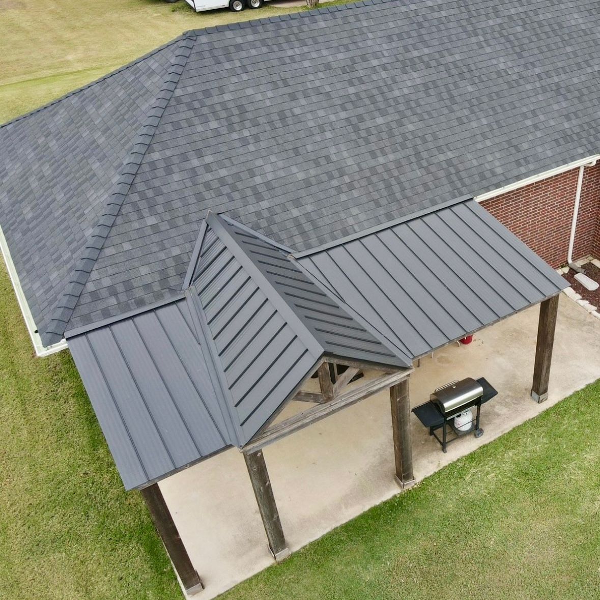 An aerial view of a house with a black roof and a porch.