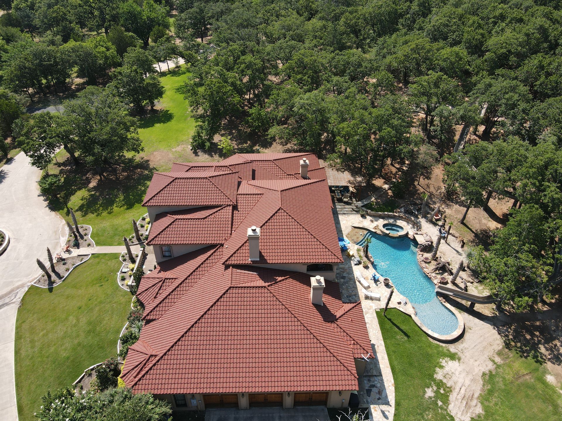 An aerial view of a large house with a pool in the backyard surrounded by trees.