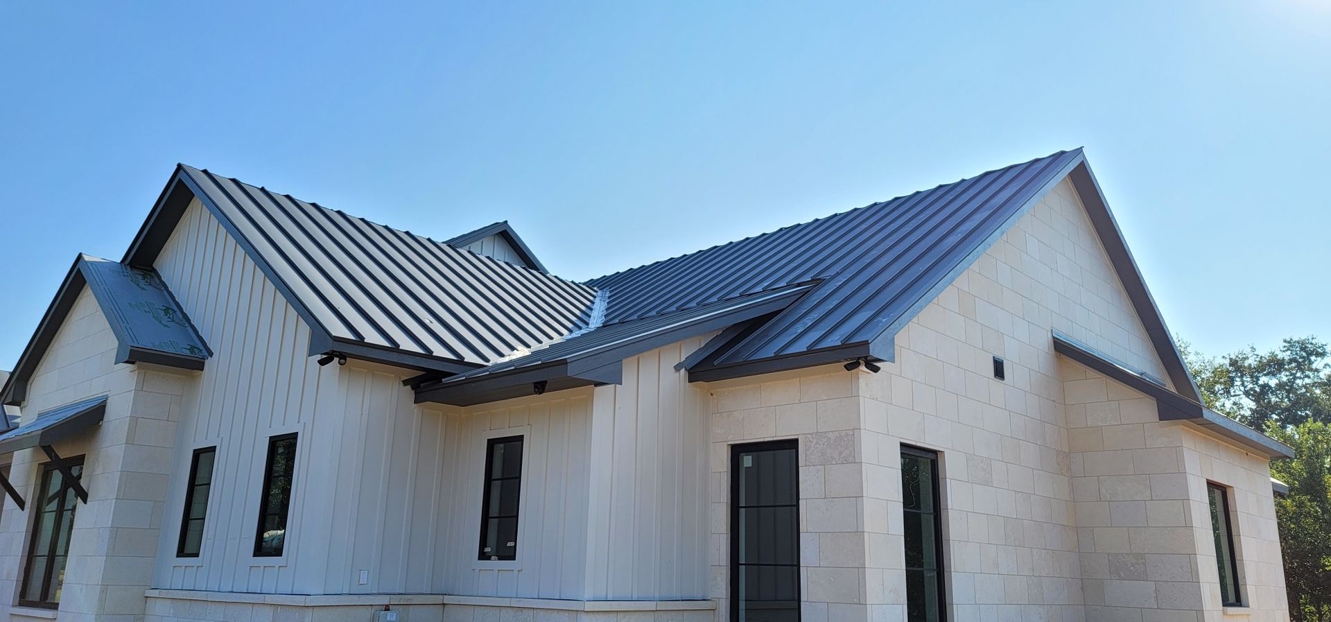 A white house with a black roof is being built.