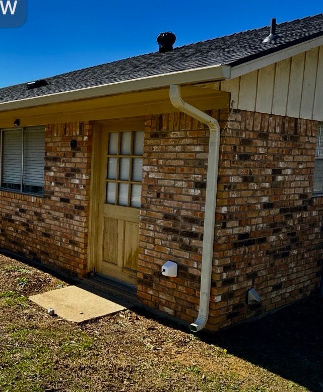 A brick house with a gutter on the side of it