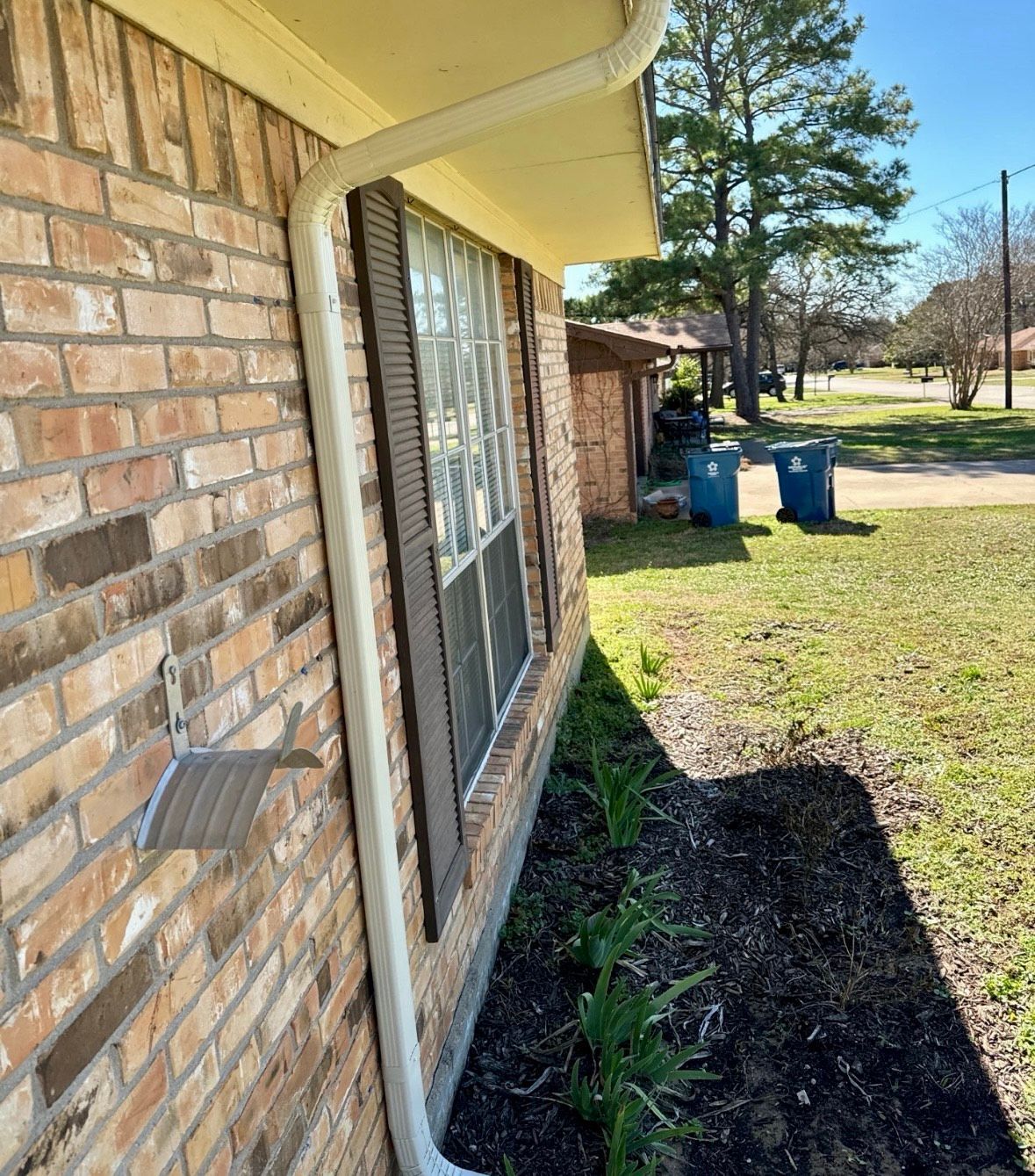 A brick house with a white gutter on the side of it.
