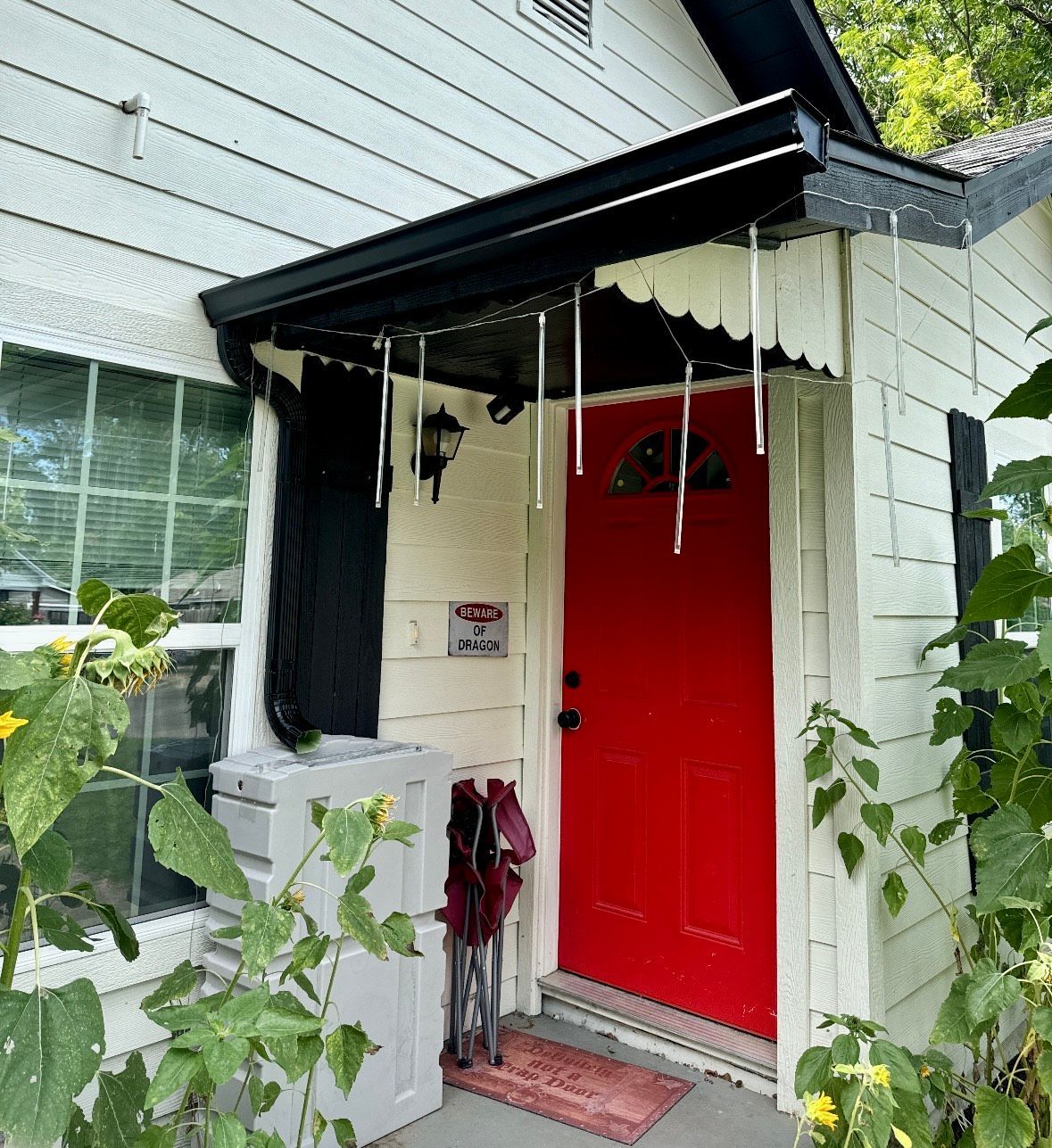 A white house with a red door and a black awning