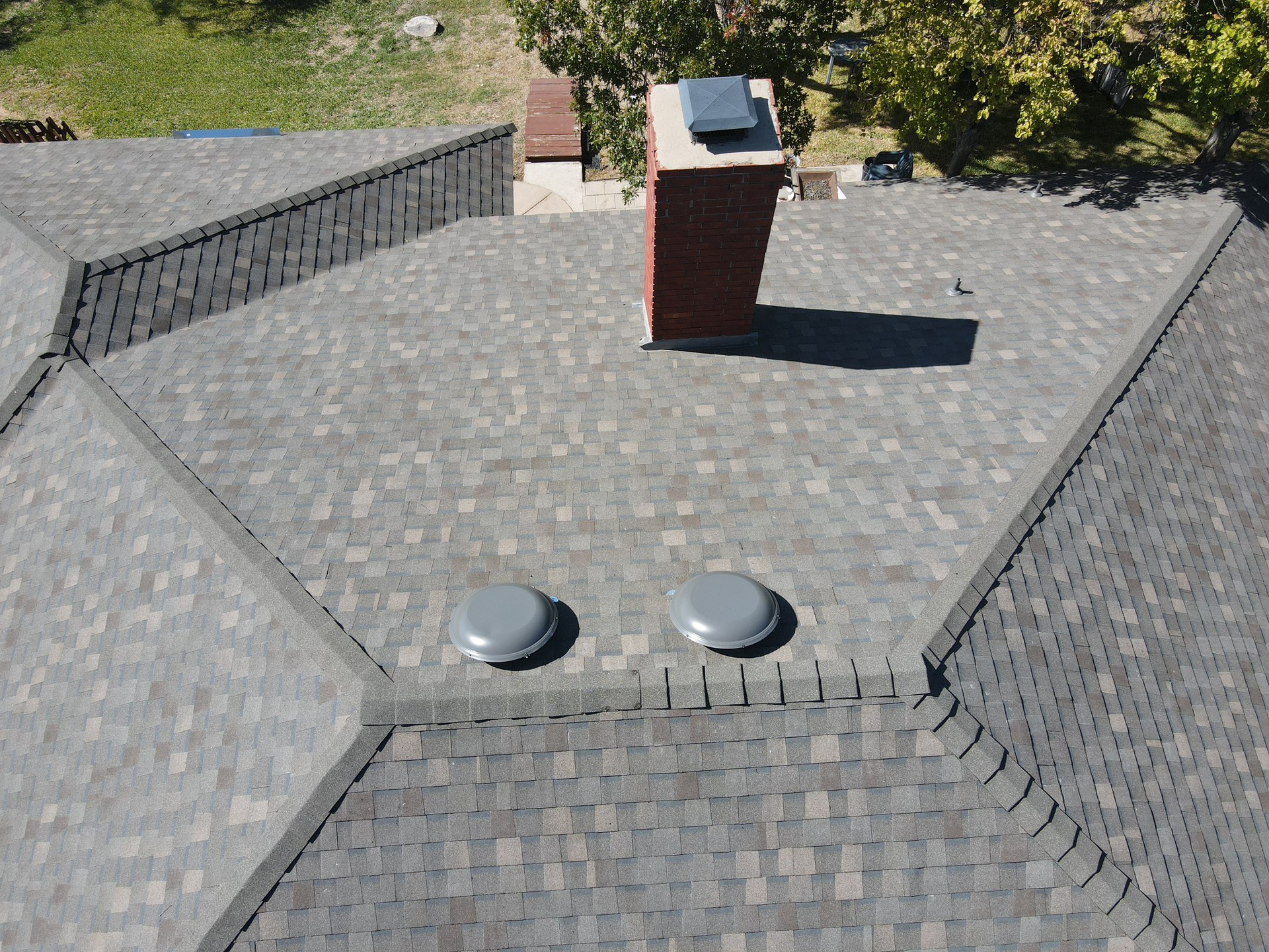 An aerial view of a roof with a chimney and two skylights.