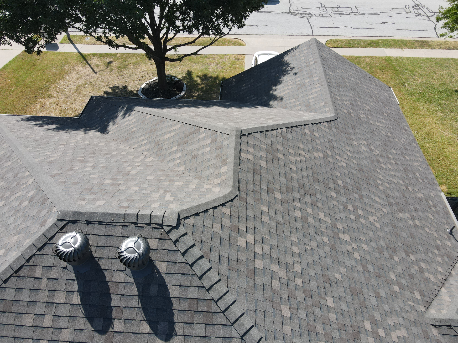 An aerial view of a roof with a tree in the background