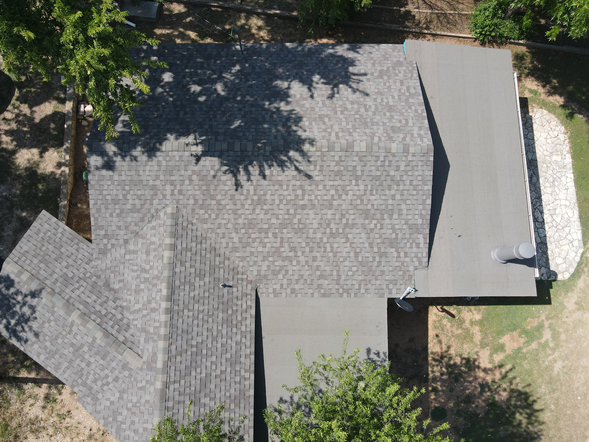 An aerial view of a roof of a house with trees in the background.
