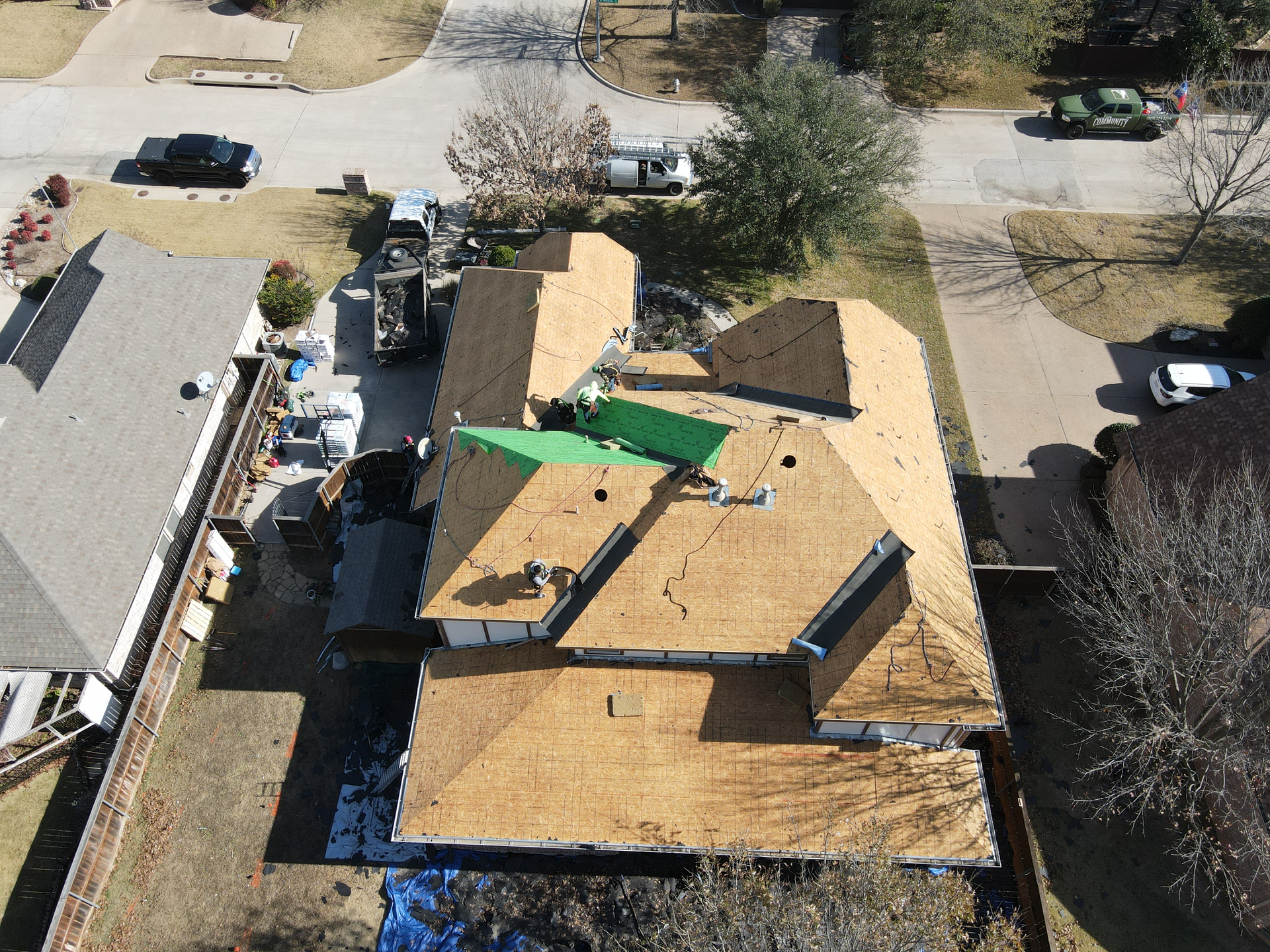 An aerial view of a house with a green tarp on the roof