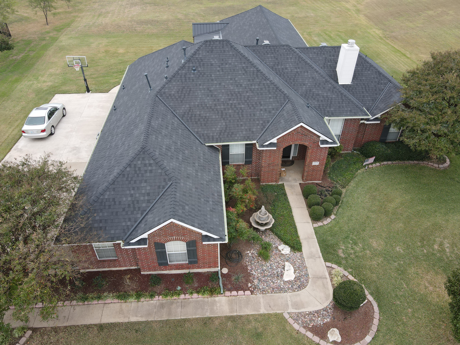 An aerial view of a large brick house with a car parked in front of it.