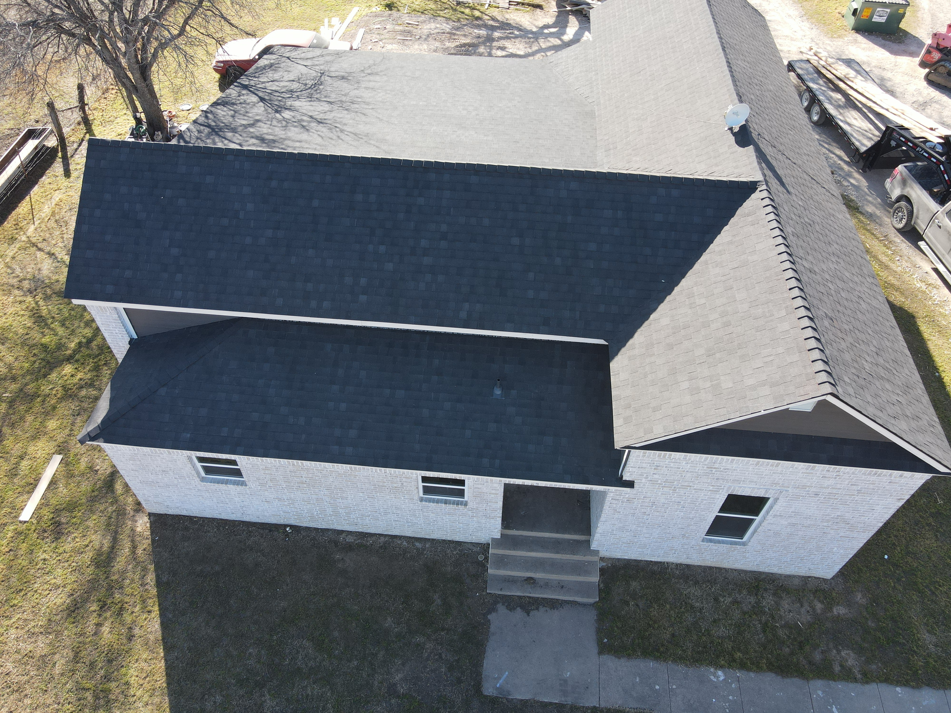 An aerial view of a white house with a black roof